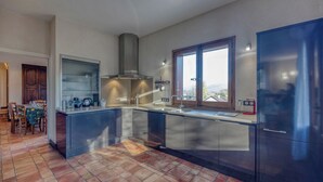 Eine moderne Küche mit einer großen Kochinsel, Edelstahlgeräten und Blick durch ein Fenster.