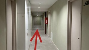 A long, narrow hotel corridor with doors on both sides and a red arrow pointing straight ahead. - Super Stylish Apartment by Wehost (Kazbegi)