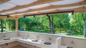 Des toilettes extérieures abritées, équipées de quatre lavabos et offrant une vue sur un parc verdoyant.