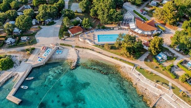 Vue aérienne d’une zone côtière avec une piscine, des bateaux et une jetée.