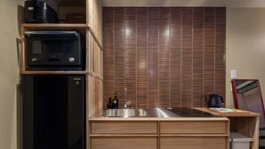 A compact kitchen with a microwave, sink, and wooden cabinets. - Shiki Homes MEIGETSU (Kyoto)