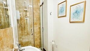 A bathroom with a shower, sink, toilet, and two framed artworks on the wall. - Comfortable One Bedroom Apartment London (London)