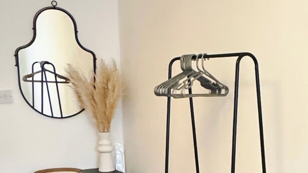 A room with a black dresser, a mirror, and a black metal drying rack. - Comfortable One Bedroom Apartment London (London)