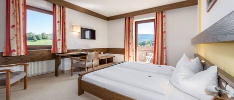 Habitación de hotel con una cama grande, un escritorio con silla, televisión y vistas al exterior.