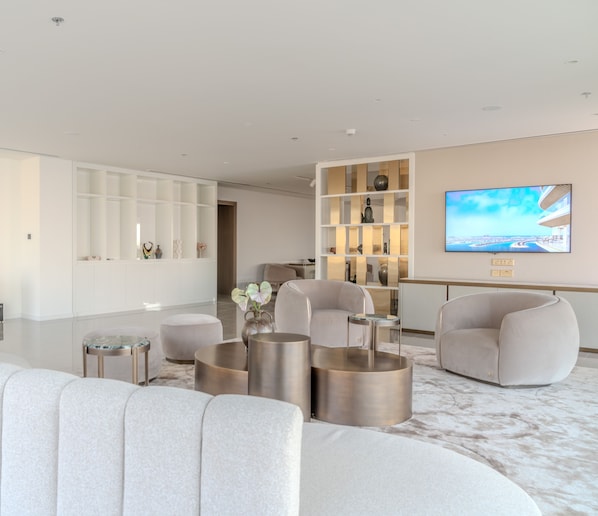 Una sala de estar moderna con un televisor de pantalla plana grande, asientos cómodos y un mueble decorativo.