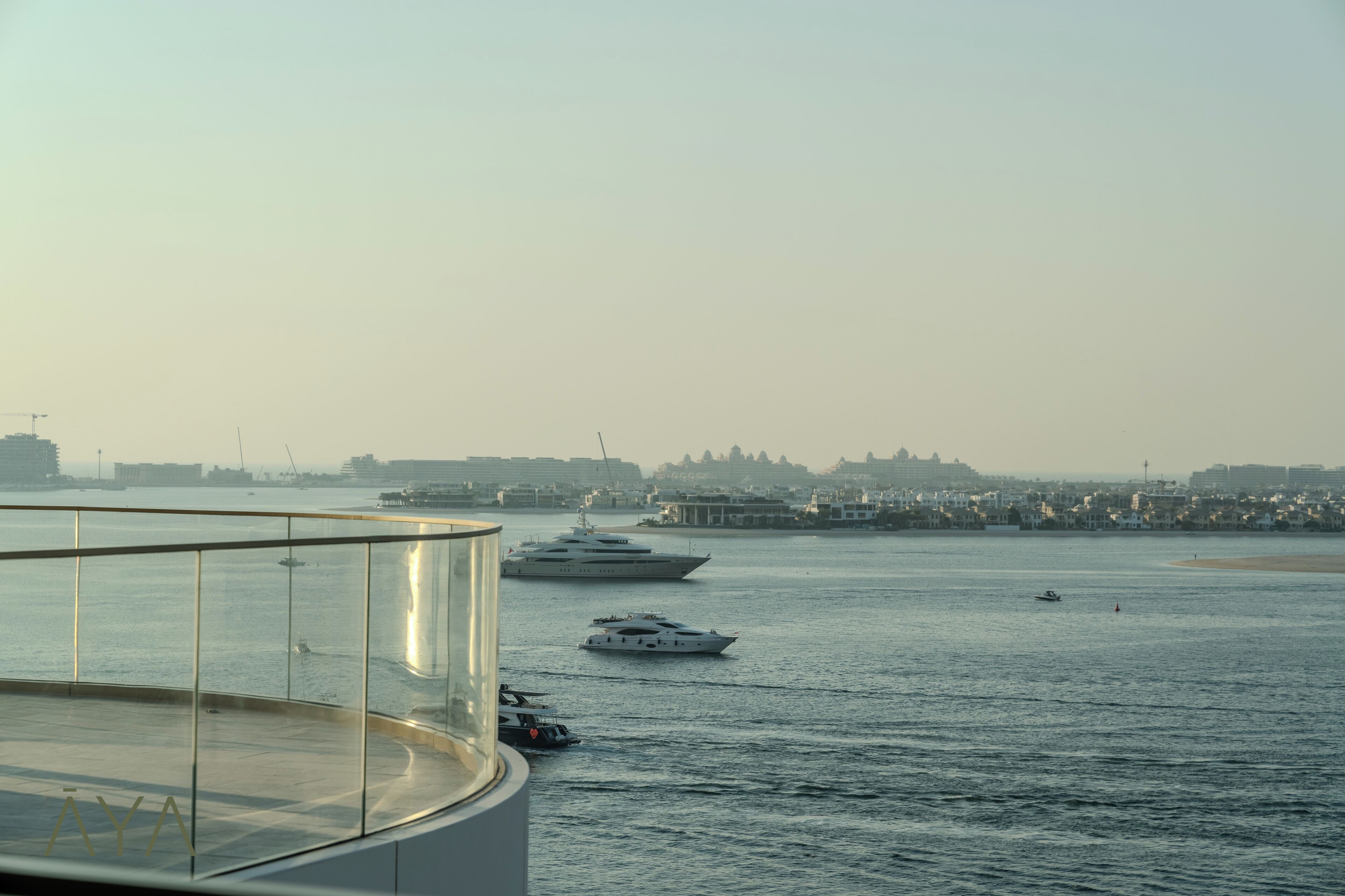 A waterfront view with multiple yachts and a distant cityscape.