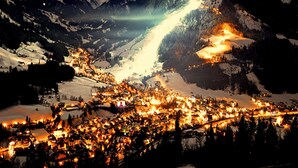 A snow-covered mountain town at night with illuminated buildings and a prominent mountain peak. - Apartment in Kirchberg Near Ski Lift (Kirchberg in Tirol)