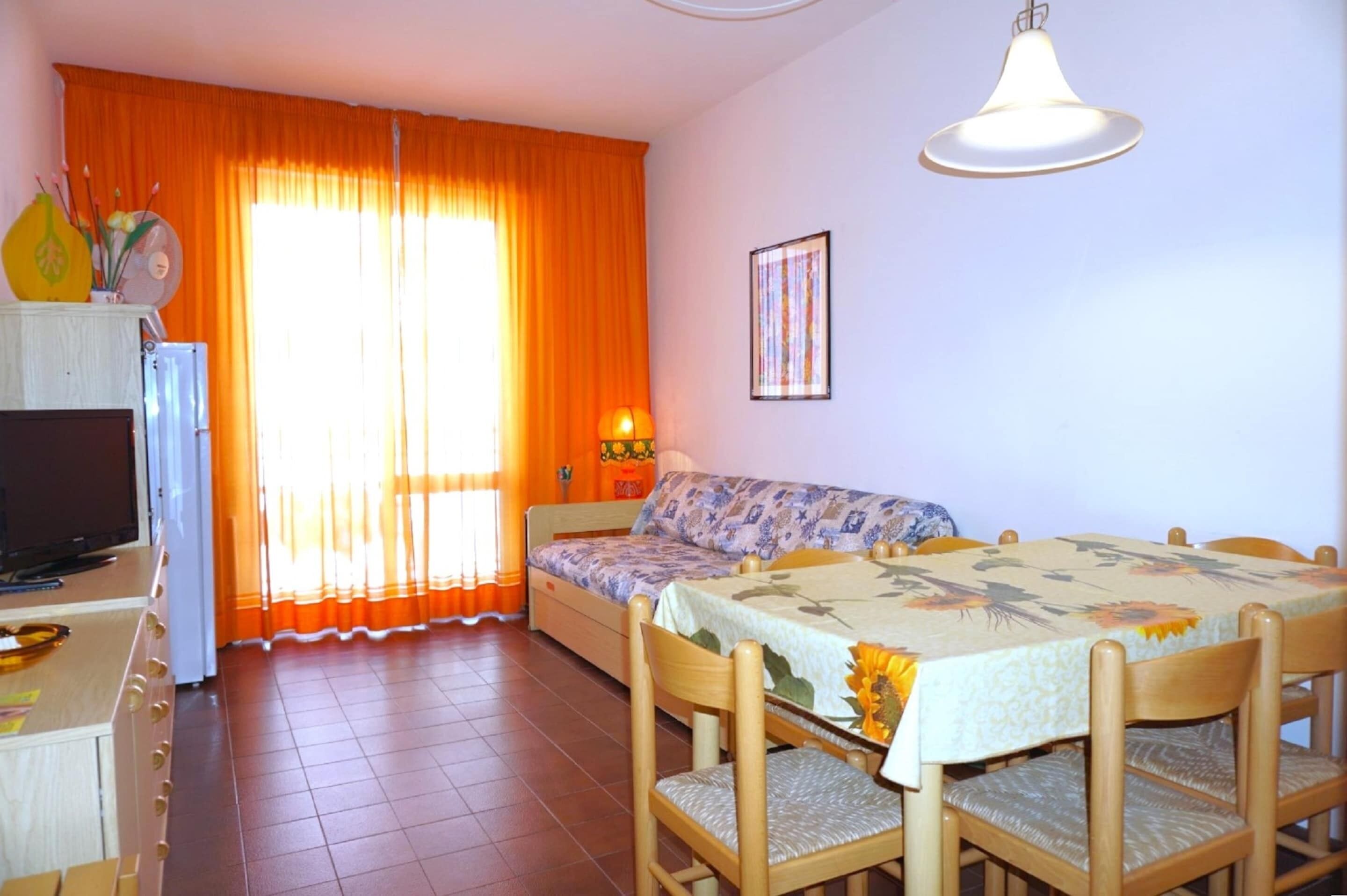 Une pièce comprenant un lit, une table à manger avec des chaises, un téléviseur et un réfrigérateur.