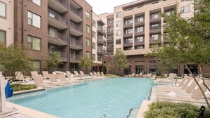 A modern apartment building with a swimming pool, lounge chairs, and a landscaped area. - Westerly (Dallas)