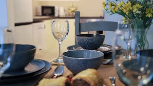 Una mesa de comedor con cuencos, una copa de vino y un florero con flores.