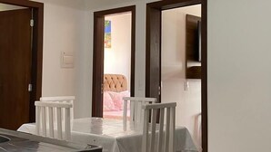 A dining area with a table and chairs, a ceiling light, and a door leading to another room. - Residencial de Aluguel Sol da Villa (Bombinhas)