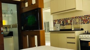 A hotel room with a bed, a television, a kitchenette, and a bathroom. - Residencial de Aluguel Sol da Villa (Bombinhas)