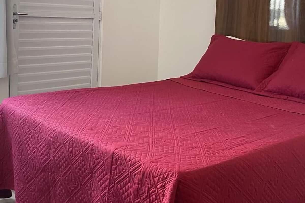 A bedroom with a bed, a door, and a painting on the wall.