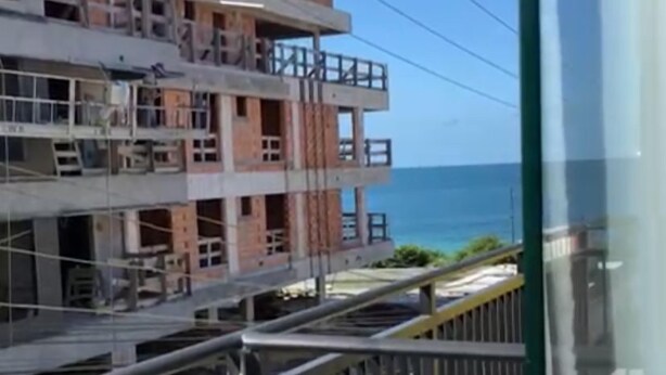 A multi-story building with balconies, a view of the sea, and a pedestrian walkway. - Residencial de Aluguel Sol da Villa (Bombinhas)