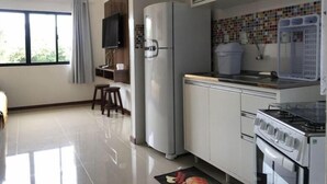 A modern kitchen with a refrigerator, stove, and a tiled backsplash. - Residencial de Aluguel Sol da Villa (Bombinhas)