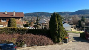 A residential area with houses, a car, and a mountain backdrop. - COZY HOME  (Plateau d'Hauteville)
