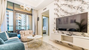 Ein modernes Wohnzimmer mit einer Couch, einem Couchtisch und einem an einer Marmorwand befestigten Fernseher.