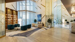 Eine großzügige Lobby mit modernem Design, ausgestattet mit einer Sitzecke mit Sofas und einem Couchtisch, einem großen Fenster für natürliches Licht und einem Empfangstresen.