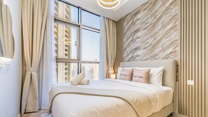 Ein modernes Schlafzimmer mit einem großen Bett, Blick auf die Stadt und einer Marmorwand.