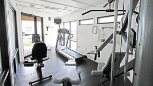 Un gimnasio con equipo de ejercicio, cinta de correr y banco para pesas.