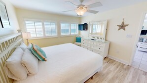 A bedroom with a bed, a dresser, a ceiling fan, and a star decoration on the wall. - Beach House 602A Gulf Front 2 BR Stunning Views and Seasonal Beach Service (Miramar Beach)