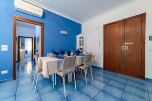A dining area with a blue tiled floor, a table set with chairs, and a wooden door. - Appartamento Sally in Sorrento (Sorrento)
