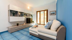 A modern living room with a sofa, a TV, a cabinet, and a window with a view. - Appartamento Sally in Sorrento (Sorrento)