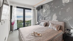 A modern bedroom with a large bed, a view of the outdoors, and a decorative wall mural. - Luxurious Villa Gabi with an infinity pool and sauna (Mihotici)
