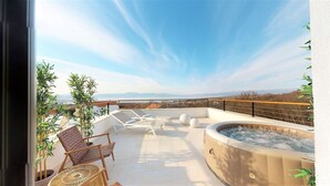 Une terrasse sur le toit équipée d’un jacuzzi, de chaises longues et de plantes en pot.