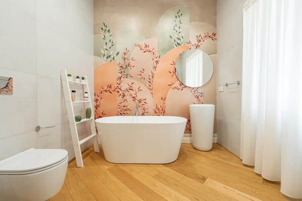 A modern bathroom with a freestanding bathtub, a round mirror, and a toilet. - Aristocrat Chiaia Bridge (Naples)
