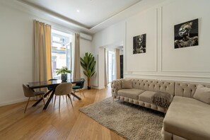Una sala de estar moderna con un sofá beige, una mesa de comedor con sillas y dos obras de arte en la pared.
