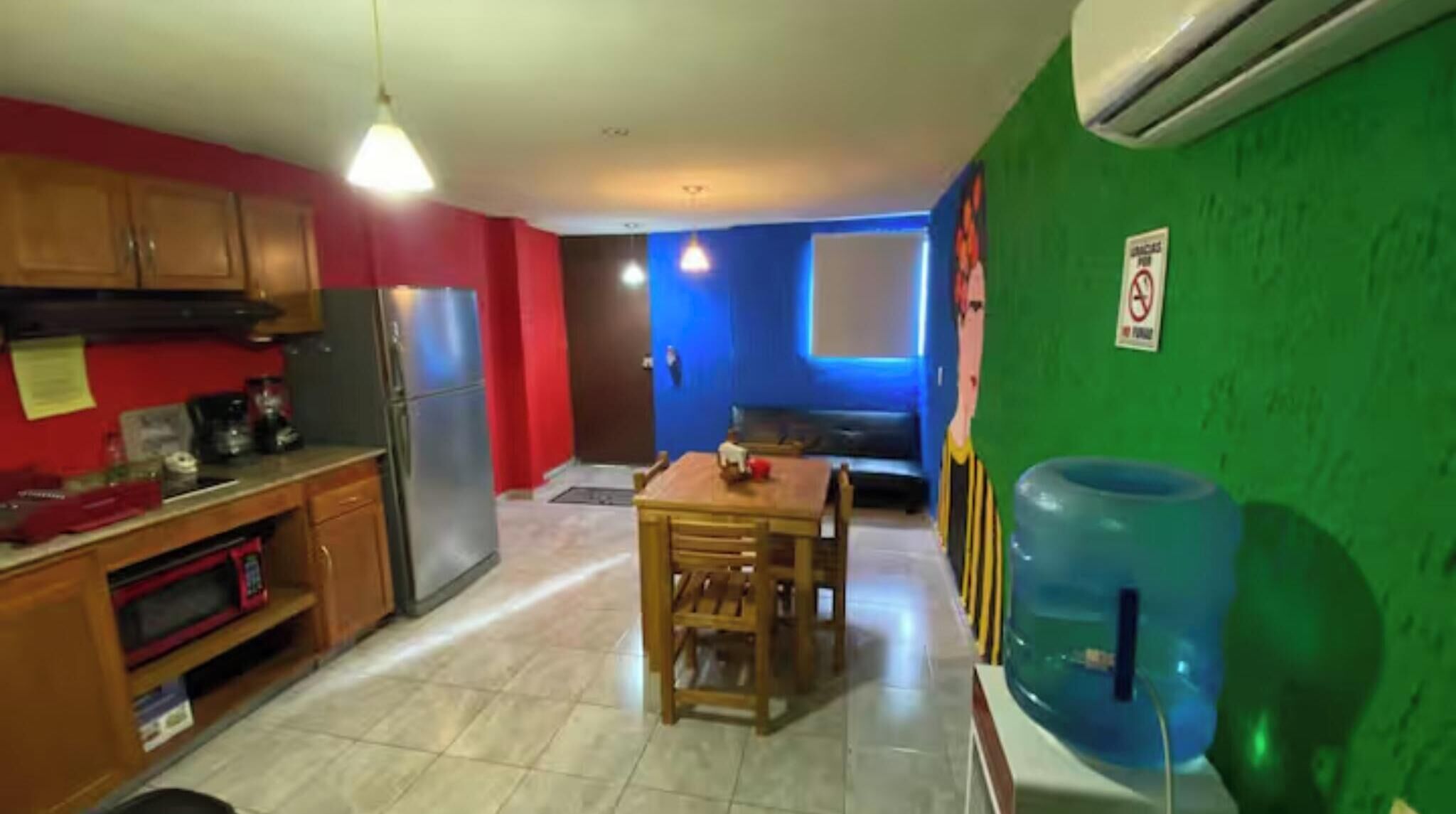 Una cocina con armarios de madera, un refrigerador y una mesa de comedor con sillas.