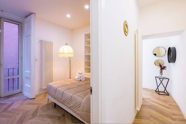 Un dormitorio con cama, lámpara de noche, radiador y puerta que da a un balcón.