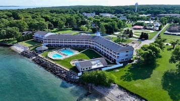 Um hotel grande e curvo, com piscina e vista para a água.