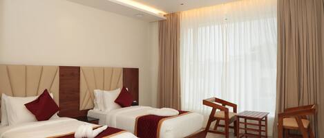 Ein Hotelzimmer mit zwei Betten, einem Deckenventilator, einem kleinen Tisch und einem Stuhl.