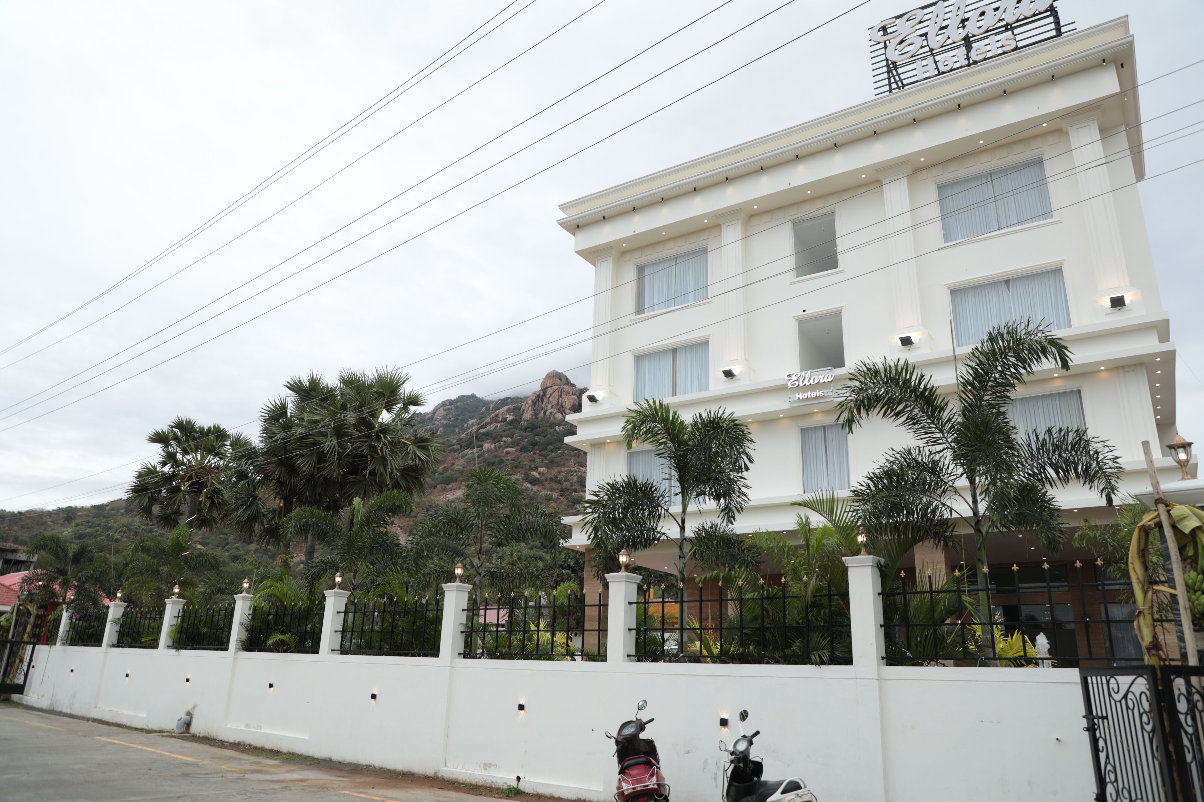 A multi-story hotel with a white facade, multiple windows, and a gated entrance.