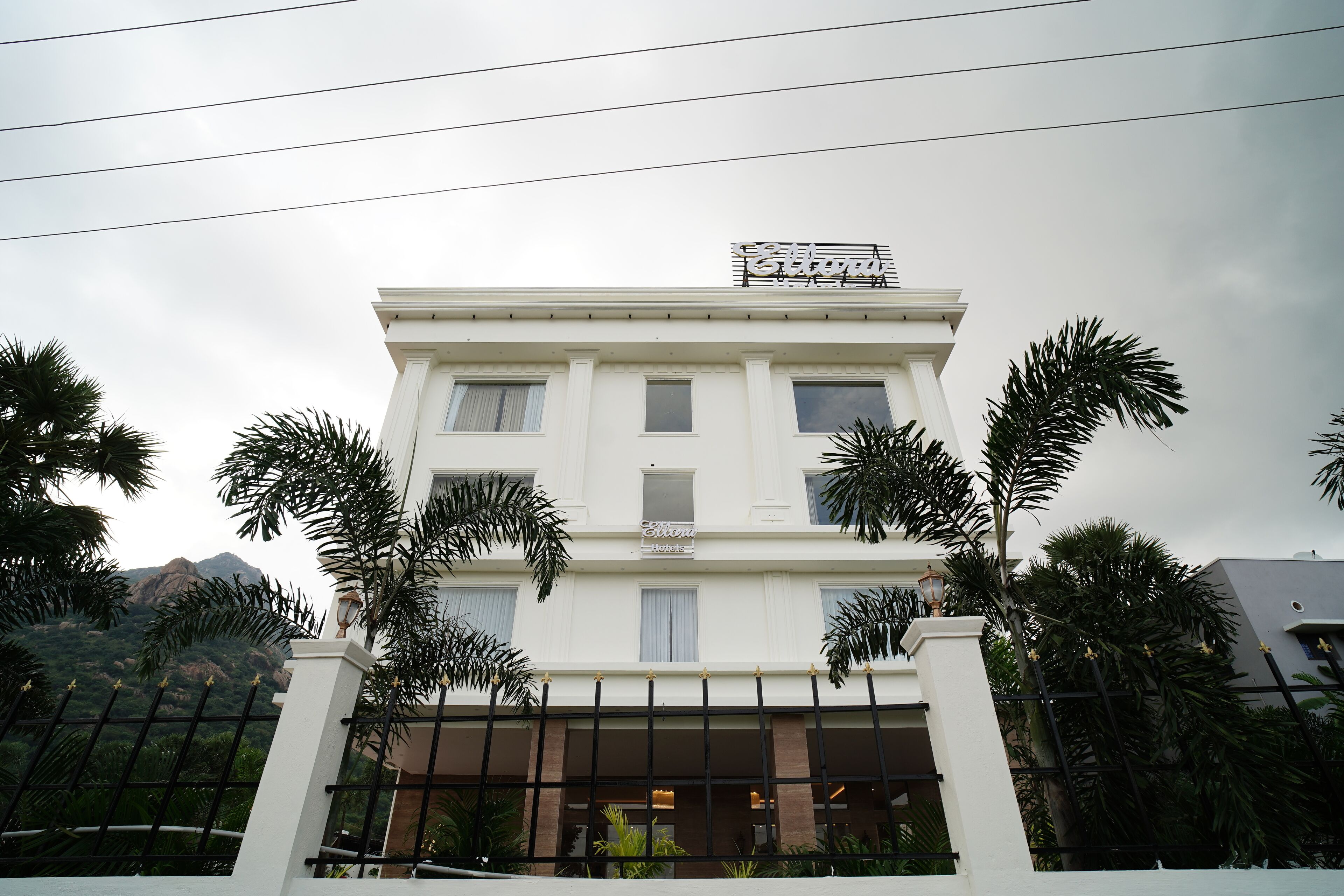 Un hotel con fachada blanca, numerosas ventanas y un letrero sobre la entrada.
