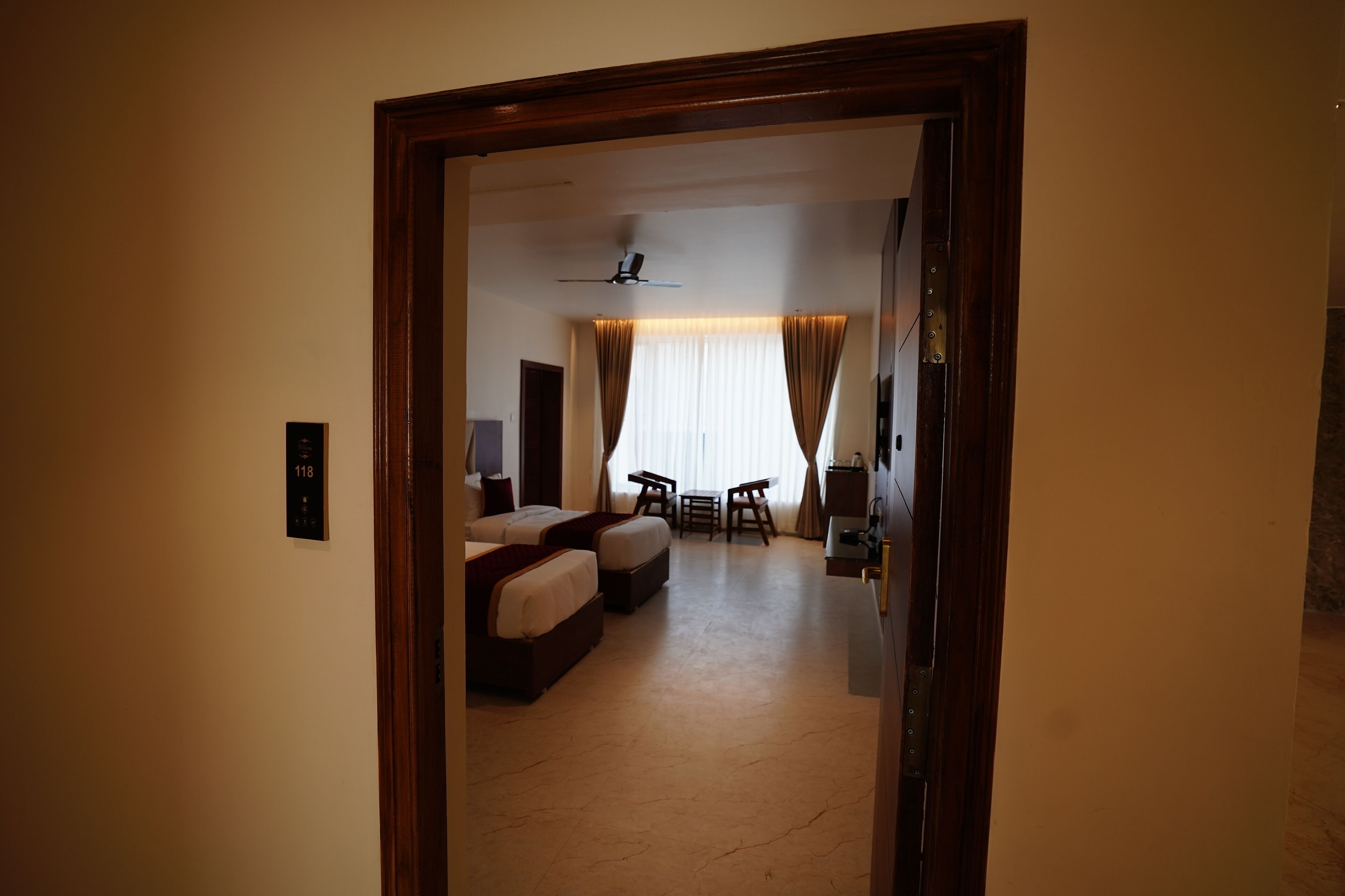 A hotel room with a bed, a desk, a chair, and a small table.