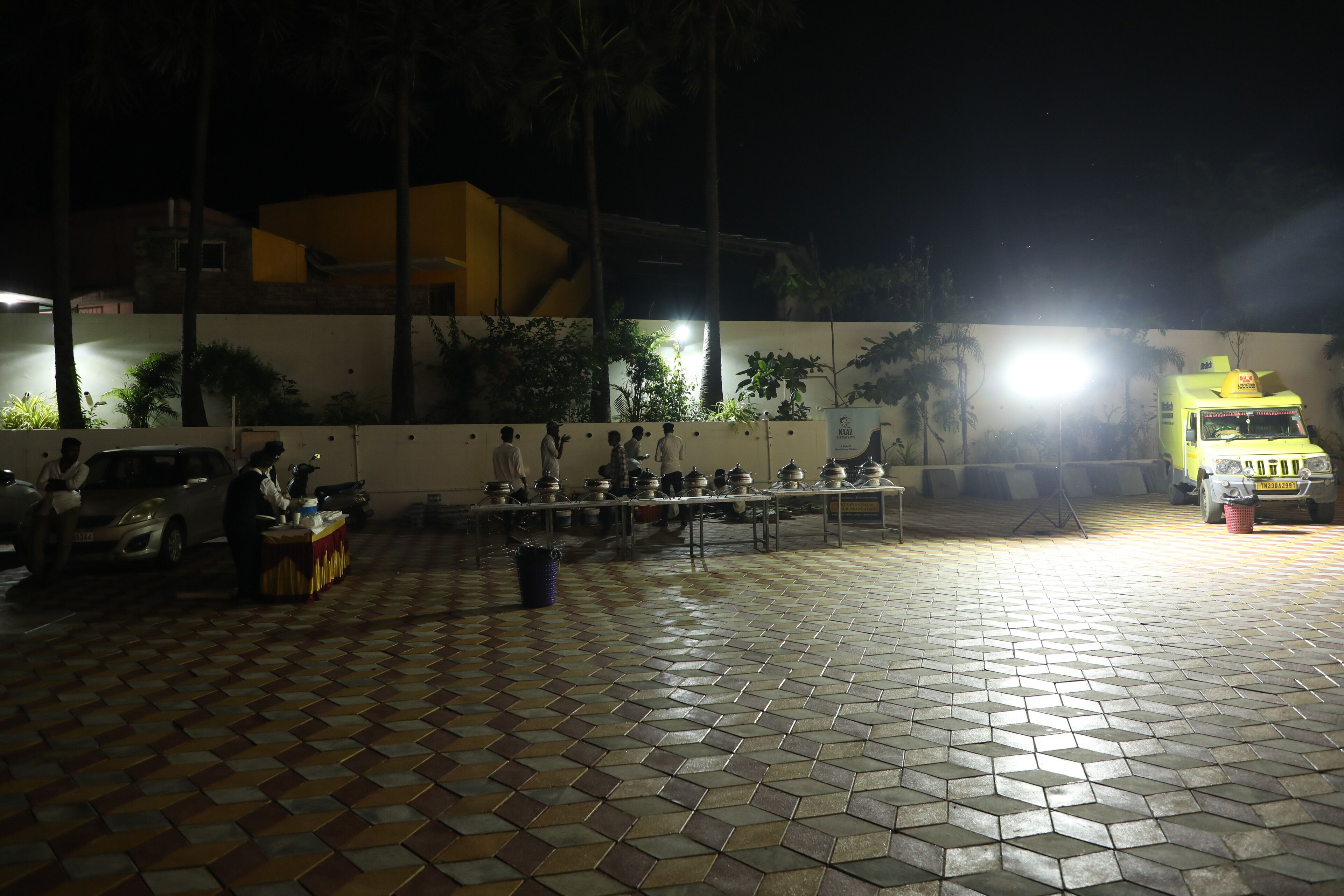 Un suelo de baldosas con una mesa y sillas dispuestas al aire libre por la noche.