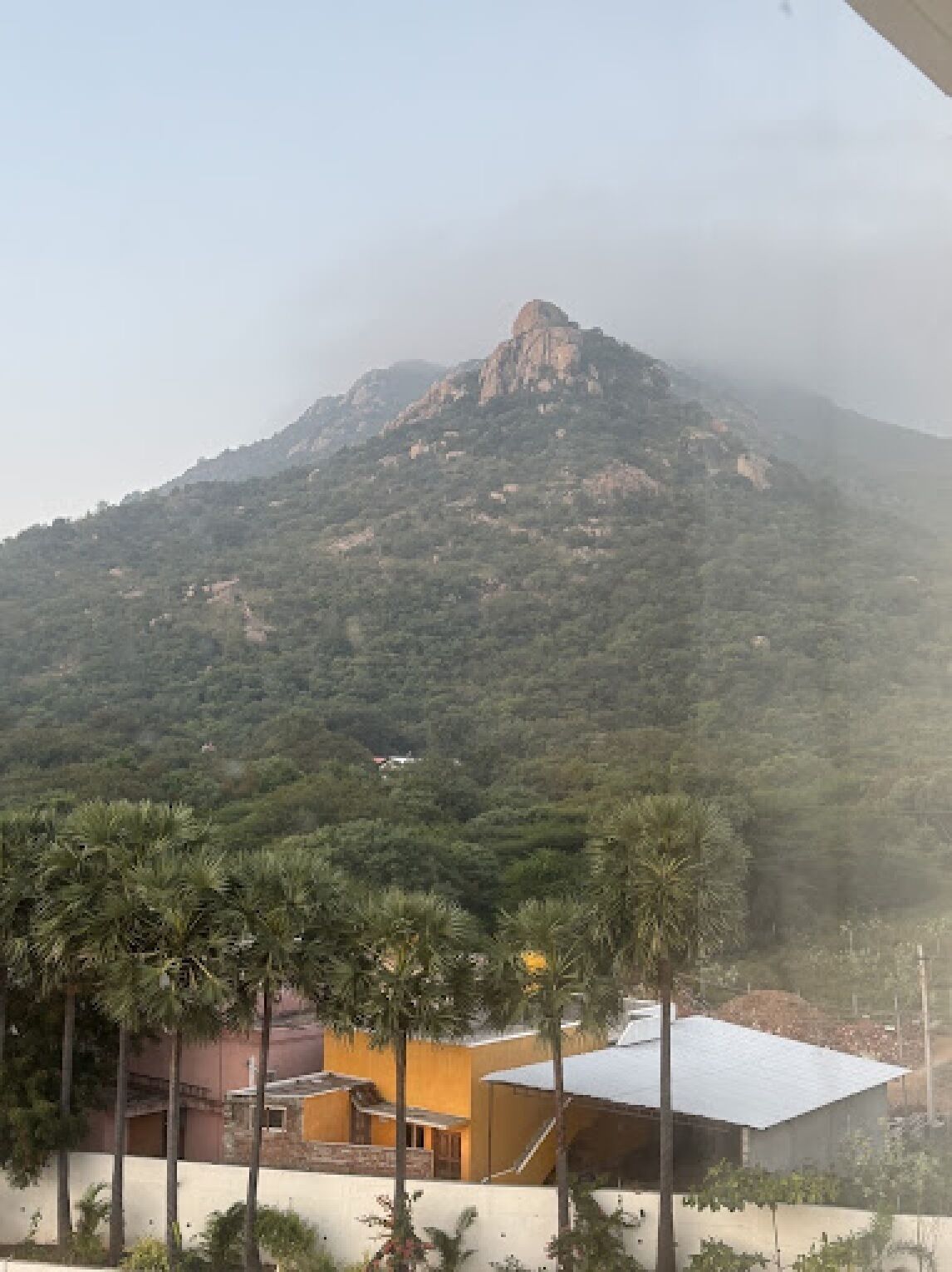 Une montagne dont le sommet est rocheux, et un bâtiment à la façade jaune, situé au premier plan.