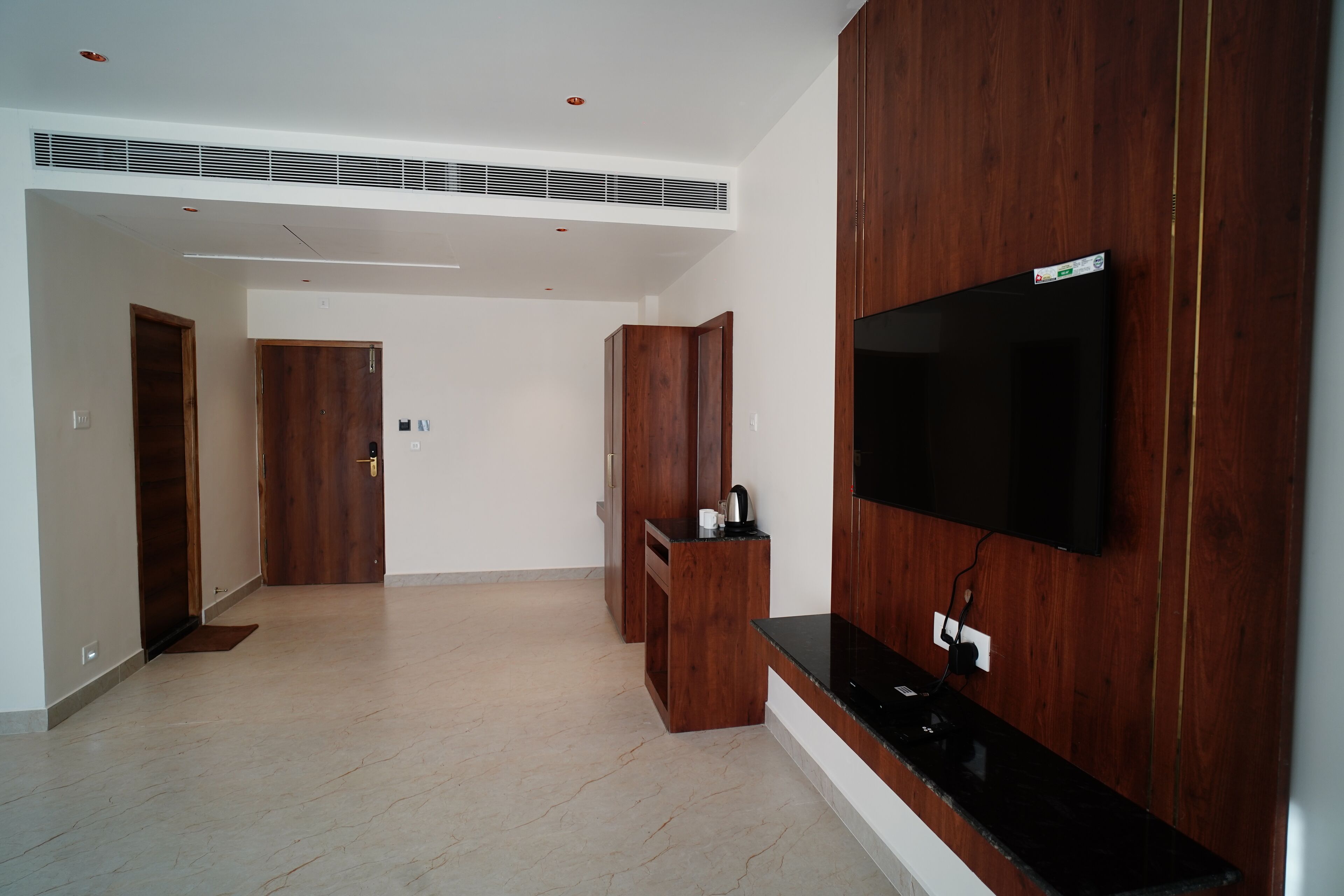 Uma sala de estar moderna com uma TV de tela plana fixada em uma parede de madeira, um móvel planejado para entretenimento e um corredor que dá para outro cômodo.
