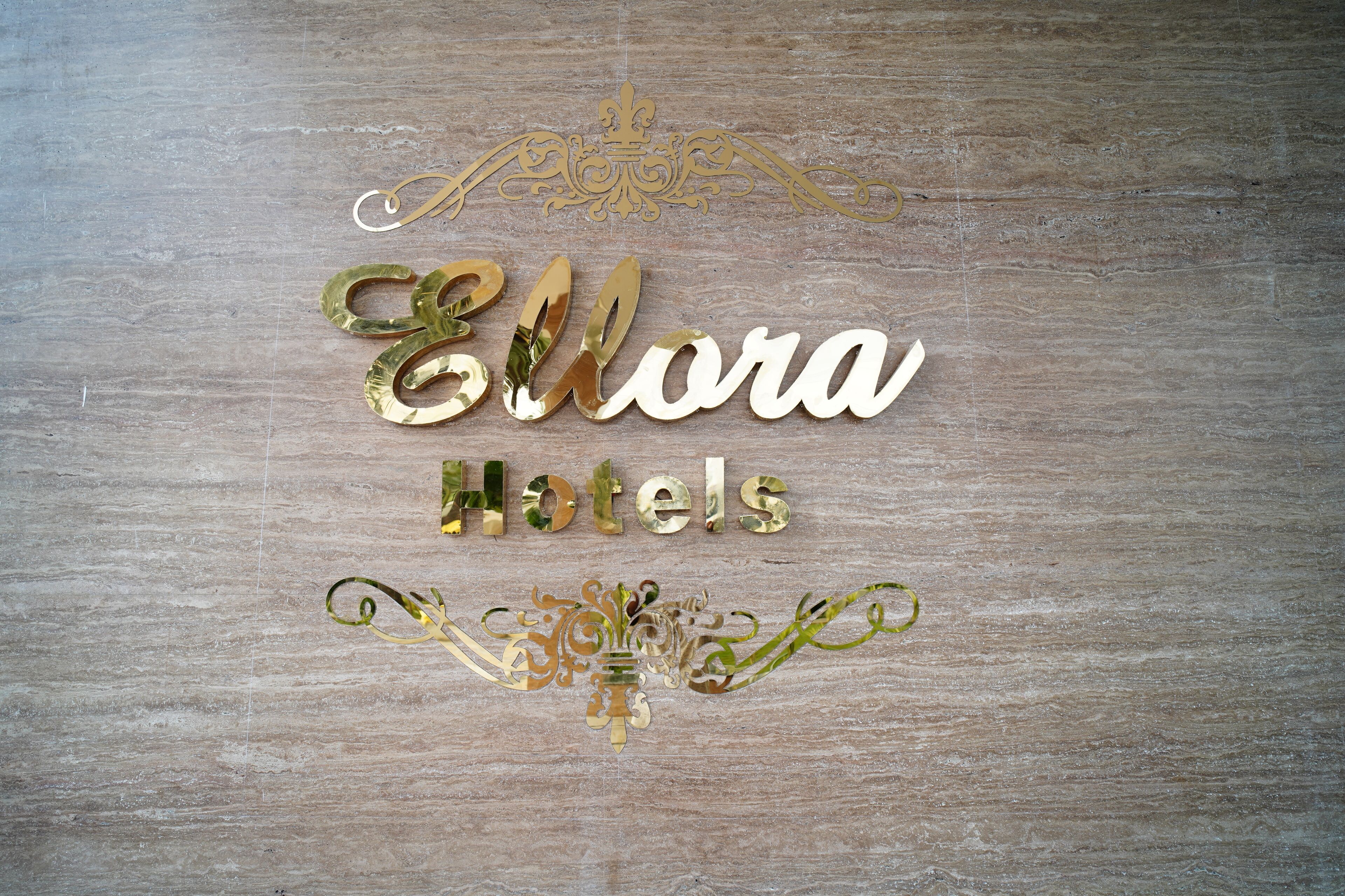 A decorative sign with the text "Ellora Hotels" on a wooden background.