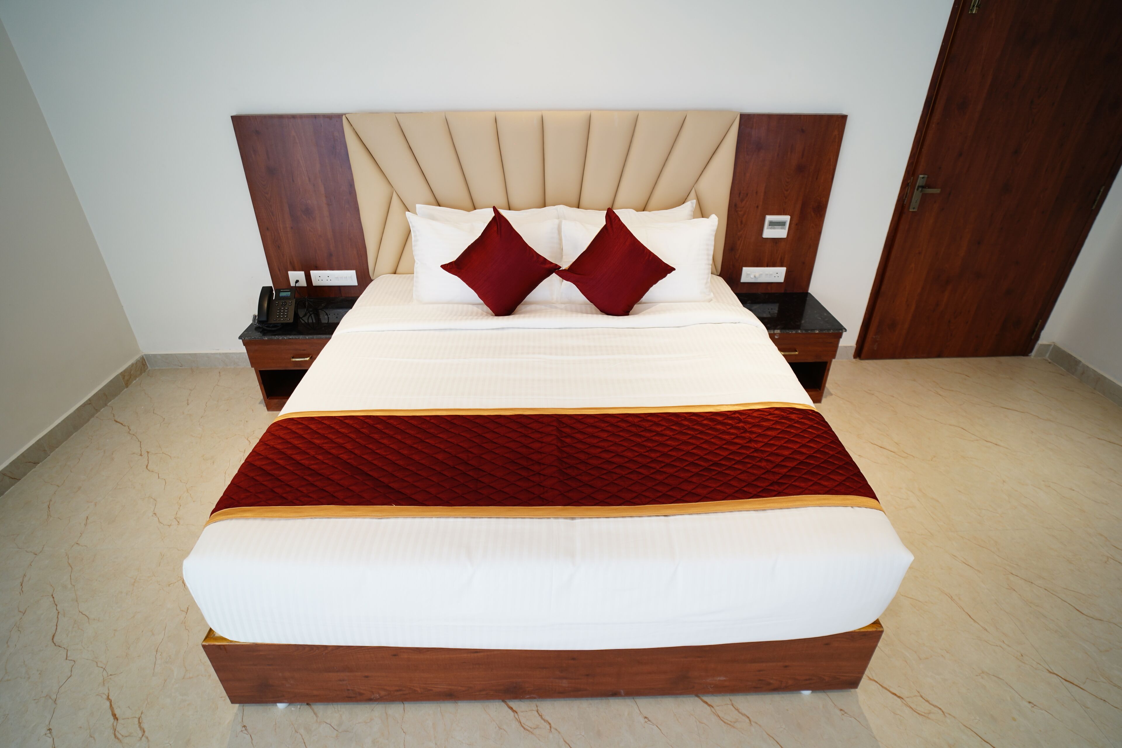 Un grand lit avec un cadre en bois, deux tables de chevet et une couvre-lit rouge et blanche.