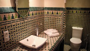 A bathroom with a tiled backsplash, a sink, a toilet, and a towel rack. - dar souran (Tangier)