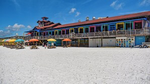 A beachside building with multiple colorful rooms and a covered seating area. - Beach House~Pet Friendly~Private Pool~Sleeps 14~3min walk to the Beach (Destin)
