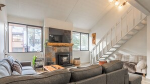Un salon moderne avec une cheminée, un grand canapé, une table basse et un escalier.