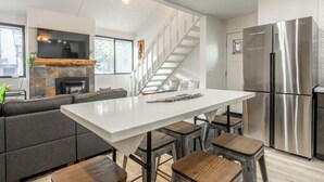 Une cuisine moderne dotée d’un îlot central, d’appareils électroménagers en acier inoxydable et d’un escalier menant à un étage supérieur.