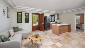 Una cocina moderna con una isla integrada, un rincón de comedor con mesa y sillas, y un sofá con cojines.