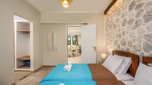 Un dormitorio con una cama, una pared de piedra, un cabecero de madera y vistas a otra habitación.