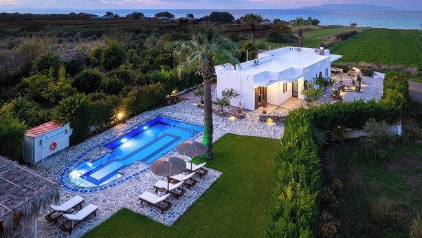 Una villa moderna con piscina, mobiliario exterior y vistas al mar.